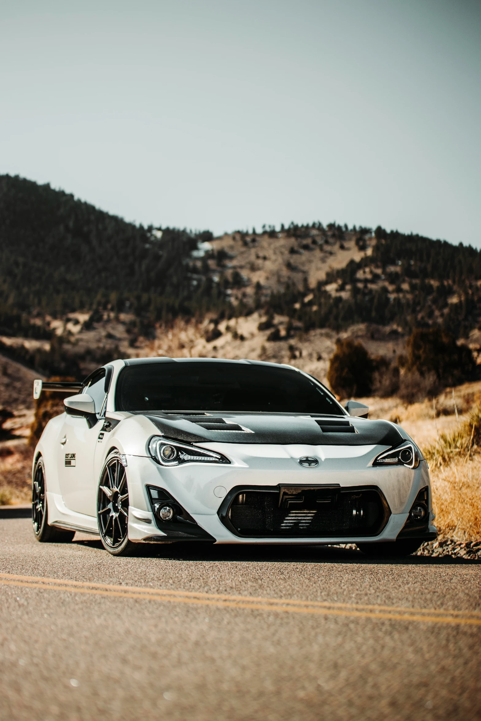 a white car driving down a road with a mountain in the background