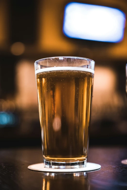 a glass of beer sitting on a bar