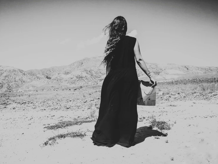 a girl walking with a handbag in the desert