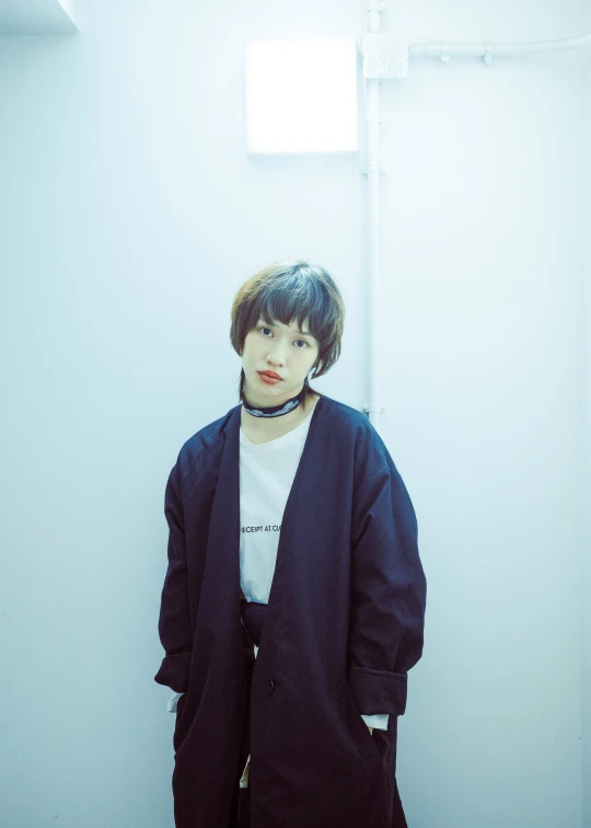 a woman leaning against a wall wearing a coat