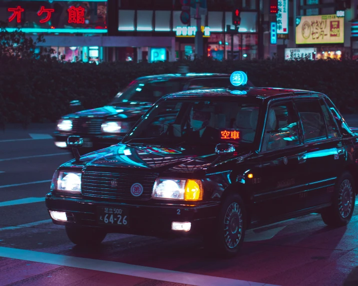 several black taxi cabs stopped at an intersection