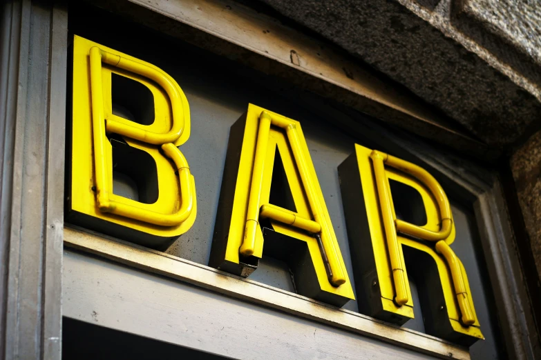 a bar with neon letters next to a window