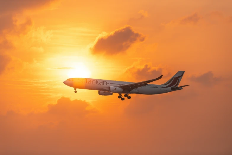 an airplane flying away into the sky at sunset