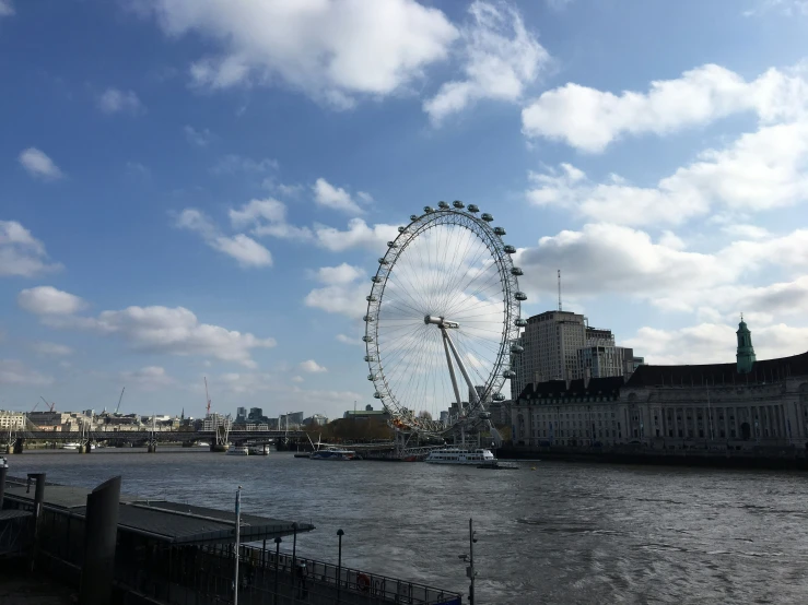 a large ferris wheel sitting on the side of a river