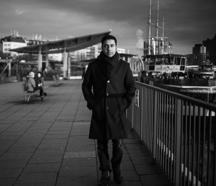 man standing with luggage on city sidewalk, looking at the camera