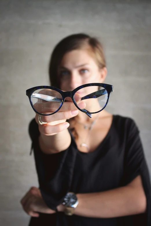 a woman with glasses, pointing at the camera
