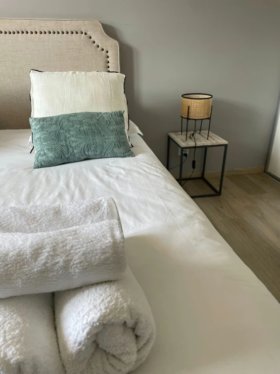 a white bed with white folded towels and some night stands