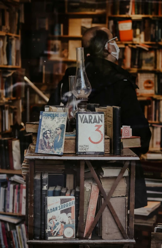 books and posters for sale on a table with a man in a mask