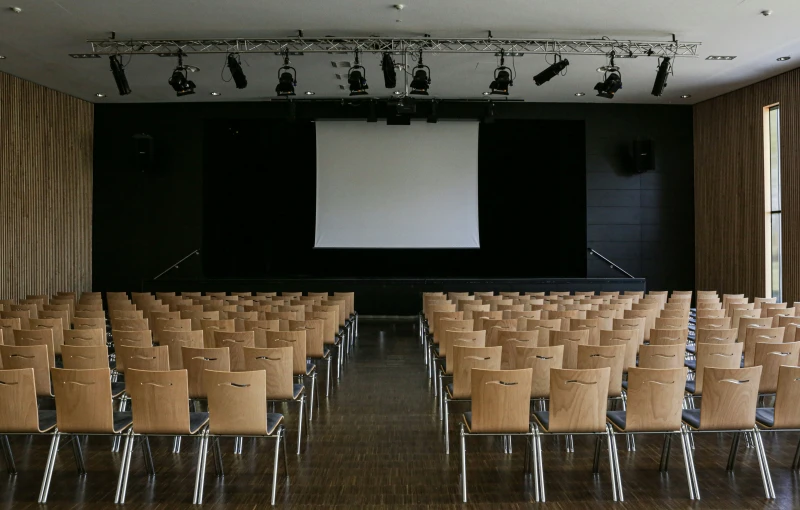 a large auditorium filled with empty chairs and projector screen