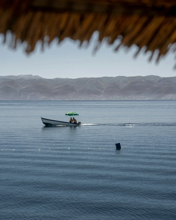 a small boat with a man driving on the water in the sun