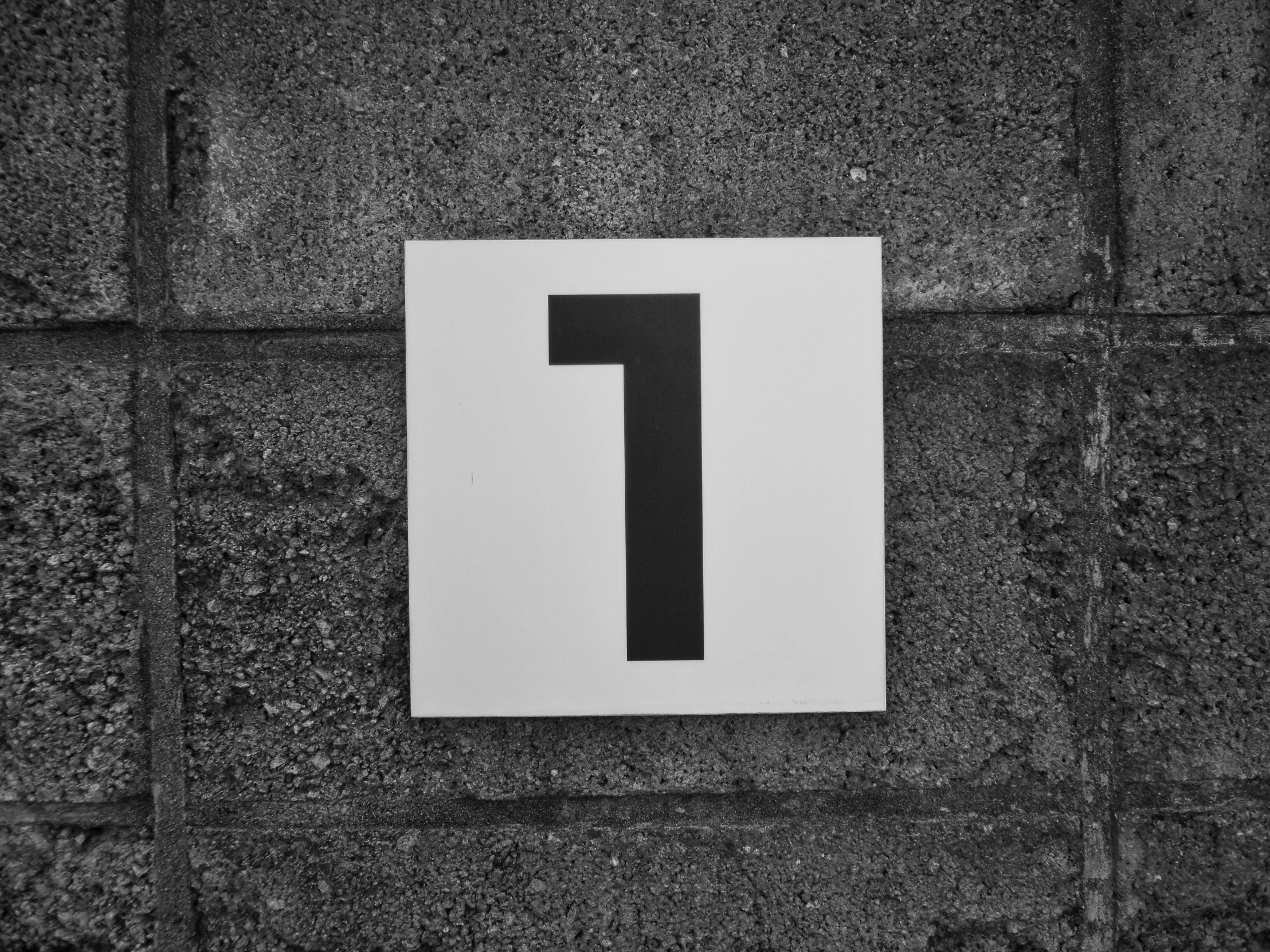 a white sign on top of a grey brick wall