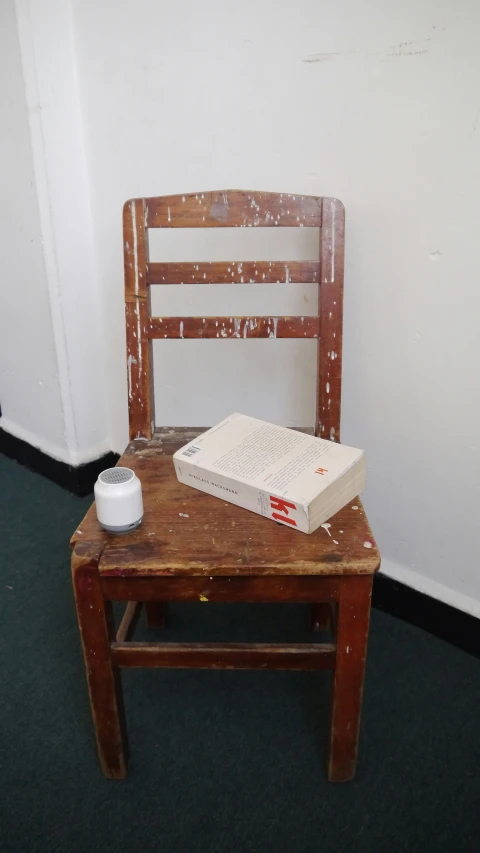 an old wooden chair next to a book sitting on the ground