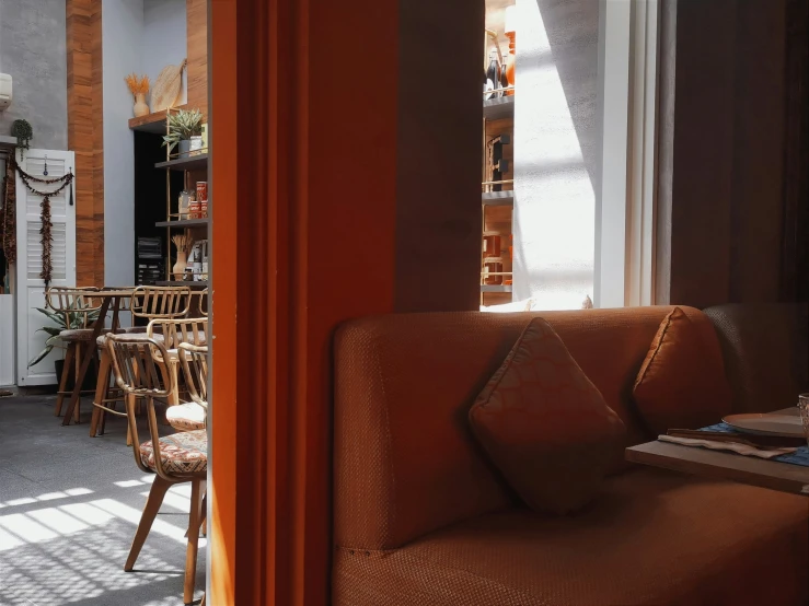 a brown couch sitting in front of a window next to a wall