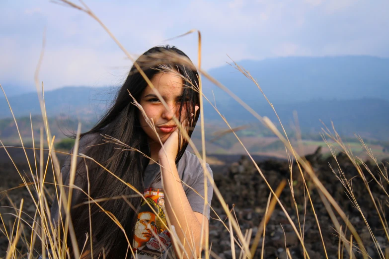 a girl sitting in grass with her hand to her face