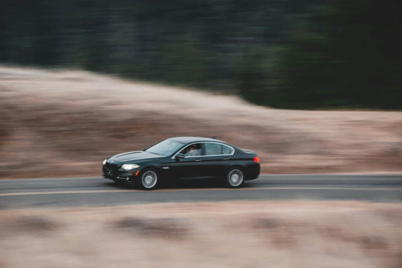 a small black car driving down a mountain road