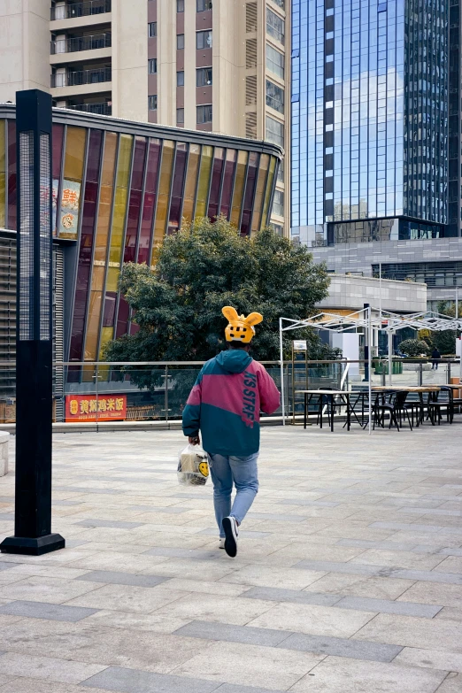 a man wearing a poke poo hat walking across a city plaza