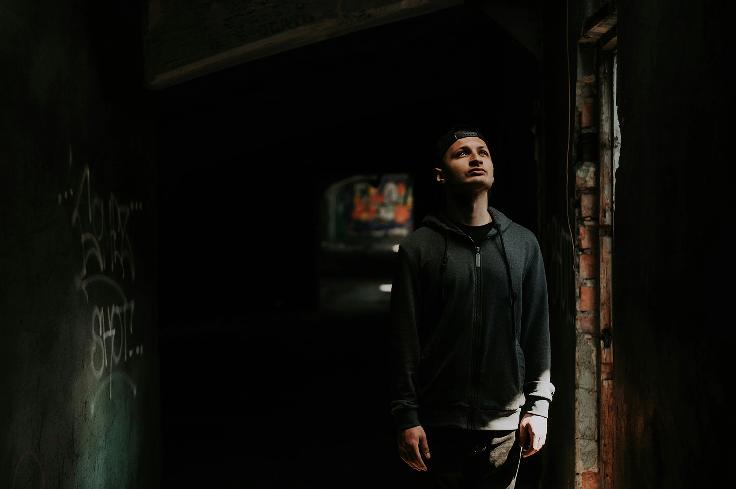 a young man standing in the doorway of an old brick building