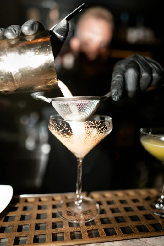 two people pouring drinks at a bar in gloves