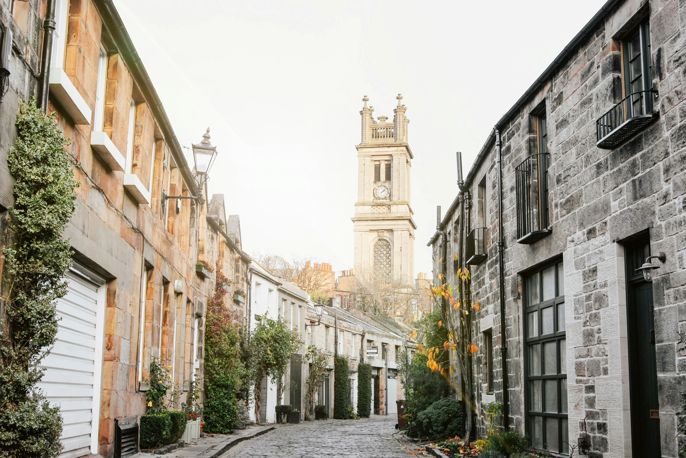 the street is lined with stone buildings, and has a tower