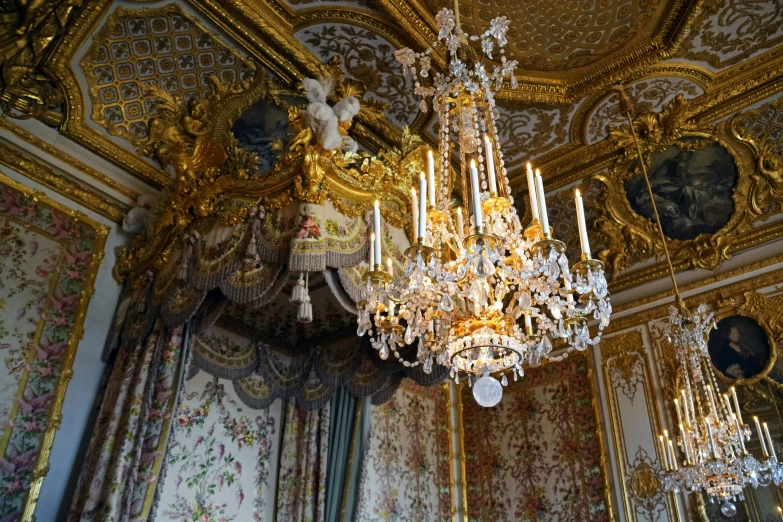 a chandelier hanging from a wall with paintings on the walls