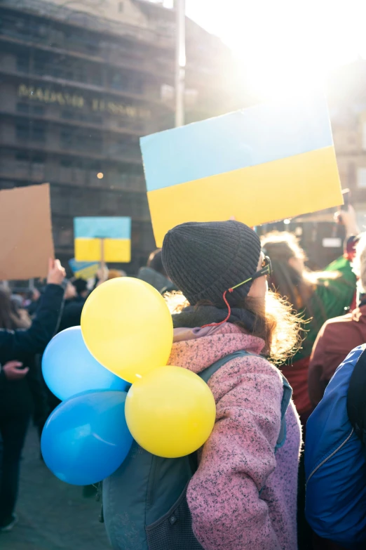 a person in front of a crowd with balloons holding up a sign