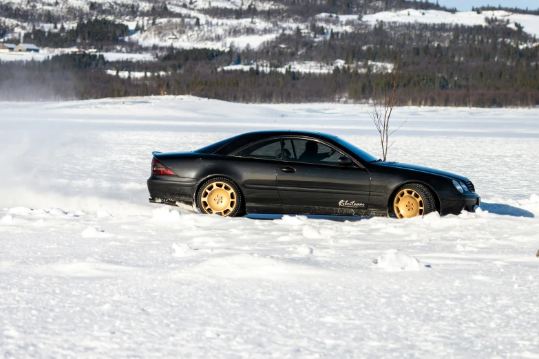 a car on snow driving with trees in the background