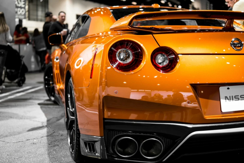 a shiny orange car at an auto show