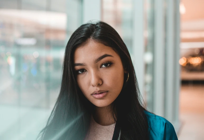 an asian woman wearing a blue jacket looking down