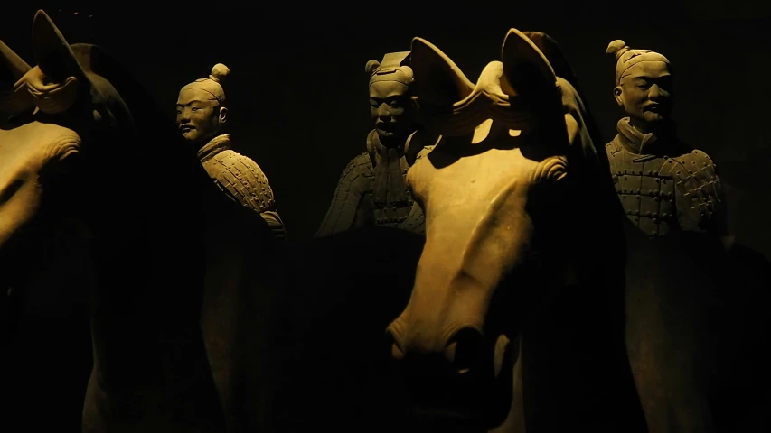 four horse heads wearing helmets in a dark room