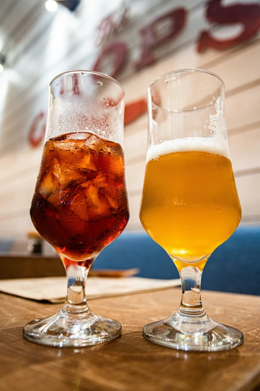 two beer glasses sitting on top of a wooden table