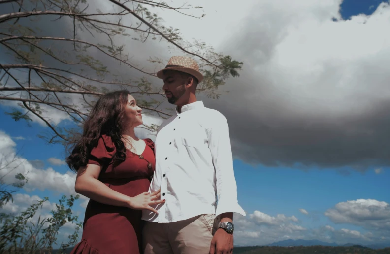 a man and woman standing next to each other under a tree