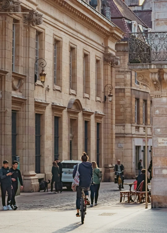 people on bicycles and cars pass by on a street