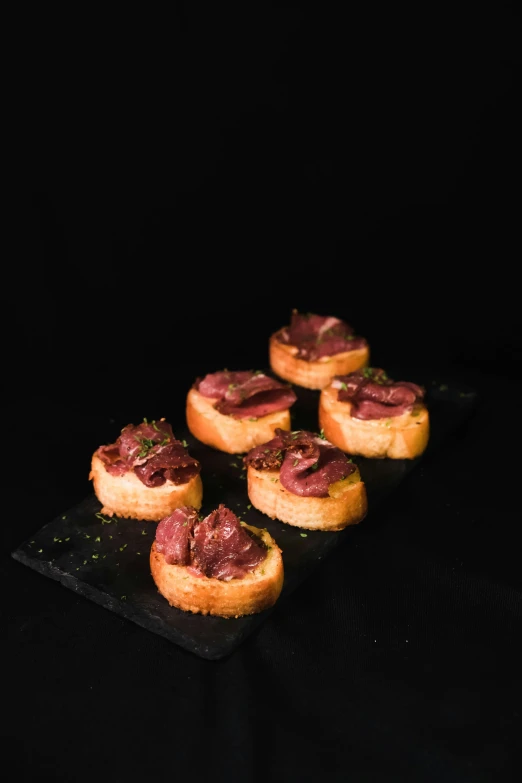 small meat filled pastries on a black plate