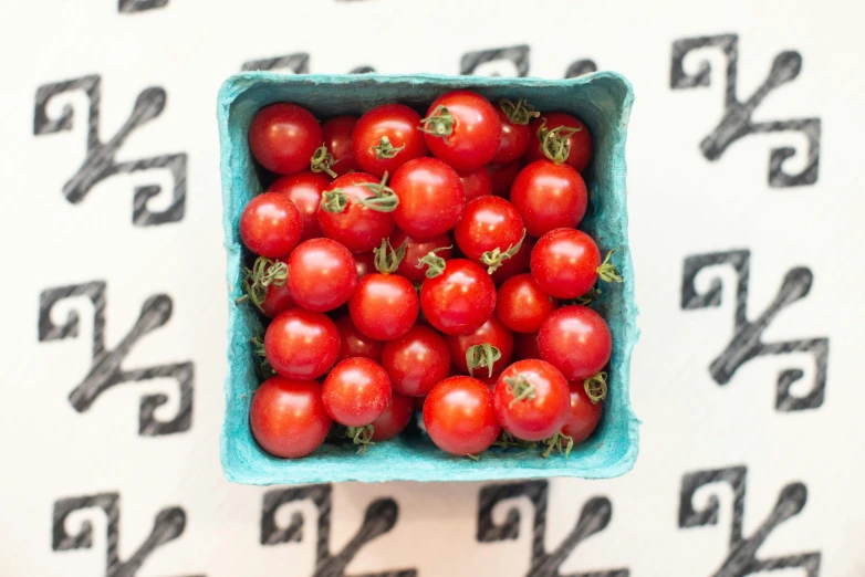 a blue bowl filled with red tomatoes sitting on top of a table