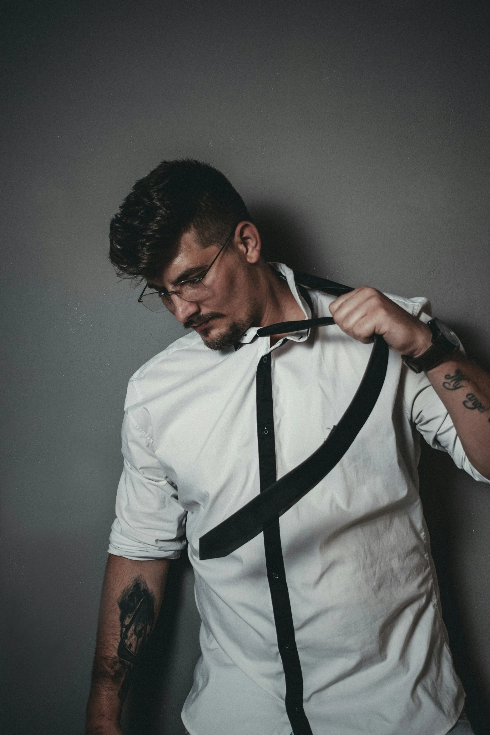 a man is putting on his suspender while wearing a white shirt