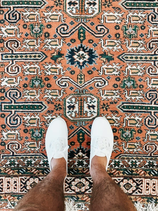 a close up view of someone's feet on an oriental carpet