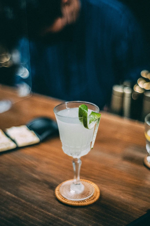 a small cocktail sits on the bar counter next to two glasses