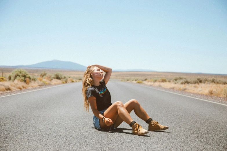 a girl sitting in the middle of a road