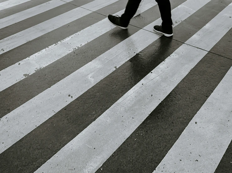 a person walking across a crosswalk in black and white