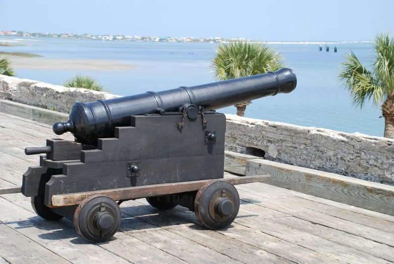 a large old metal cannon is on a wooden platform