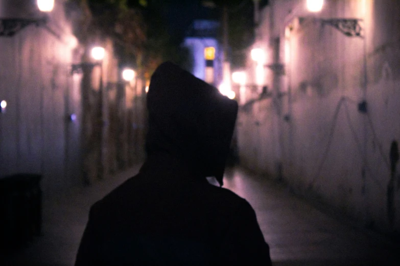 a person walks through a narrow street in the dark