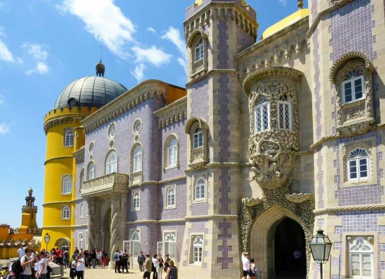 people are standing outside a colorful building with columns