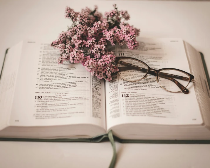an open book with glasses and flowers on top of it