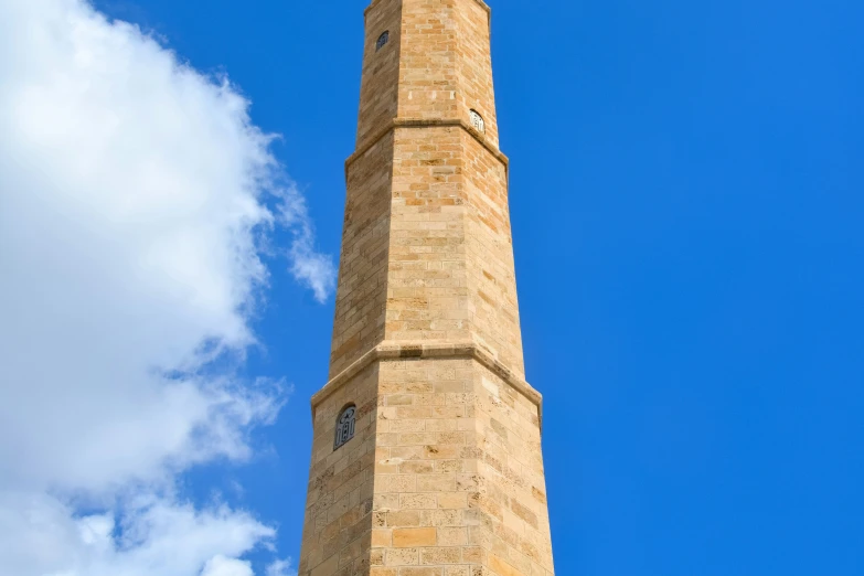 the large stone clock tower has a weather vane on it's side