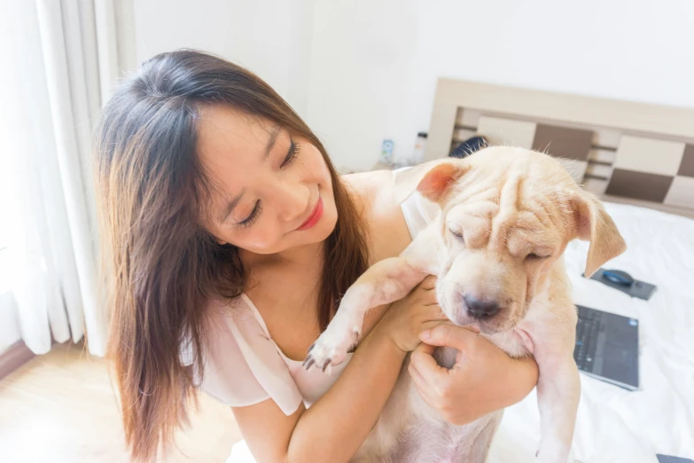 a woman holding her little dog on the bed