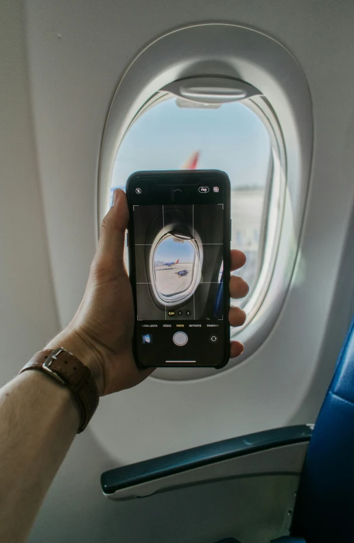 a person holds up a phone that is showing a view of a plane