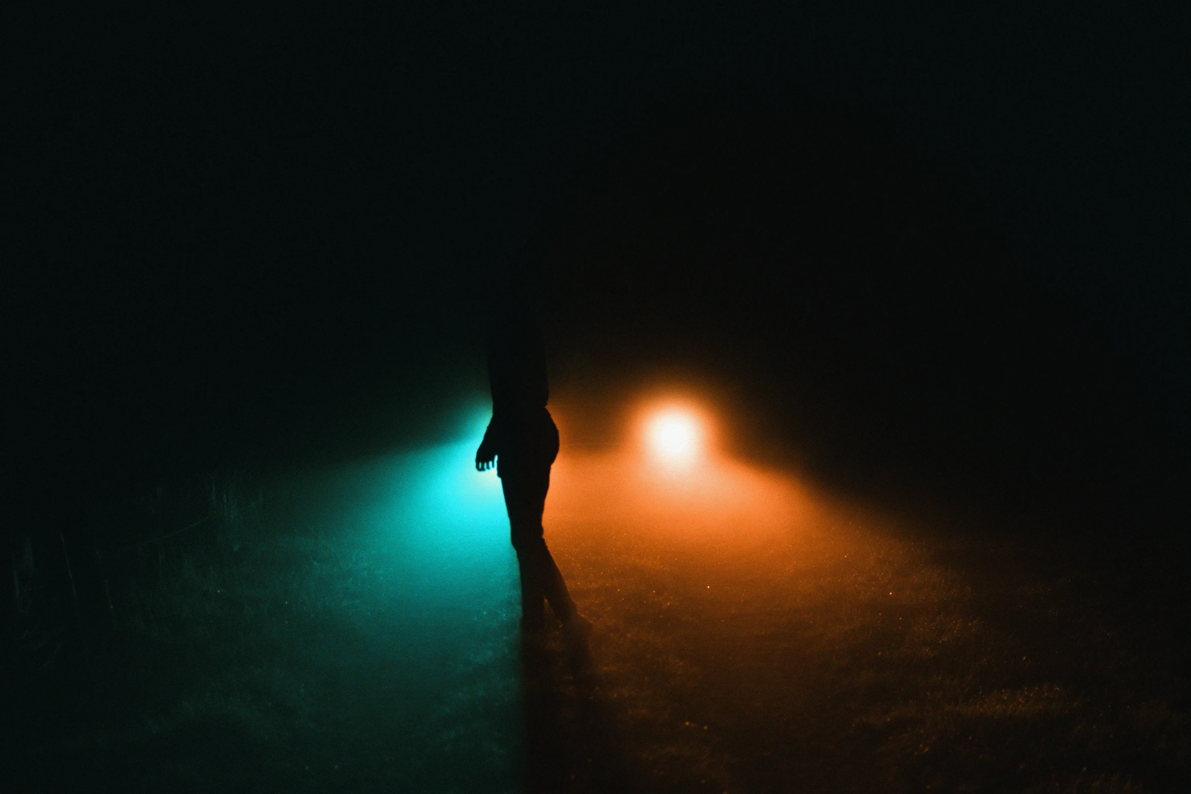 a person stands in the dark with a lit umbrella