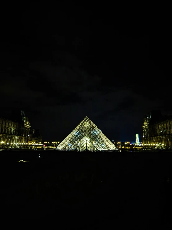 the pyramid in the middle of the city is lit up at night