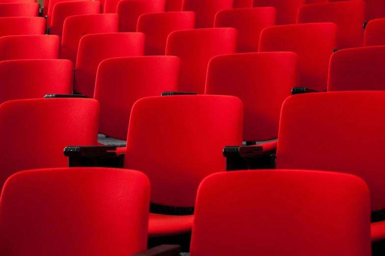 a row of chairs with red seats lined up in rows