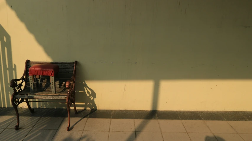 a chair sitting on a tiled floor with a shadow cast on the wall